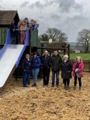 7 children at the top of a slide with a 6 adults standing next to it on the ground 